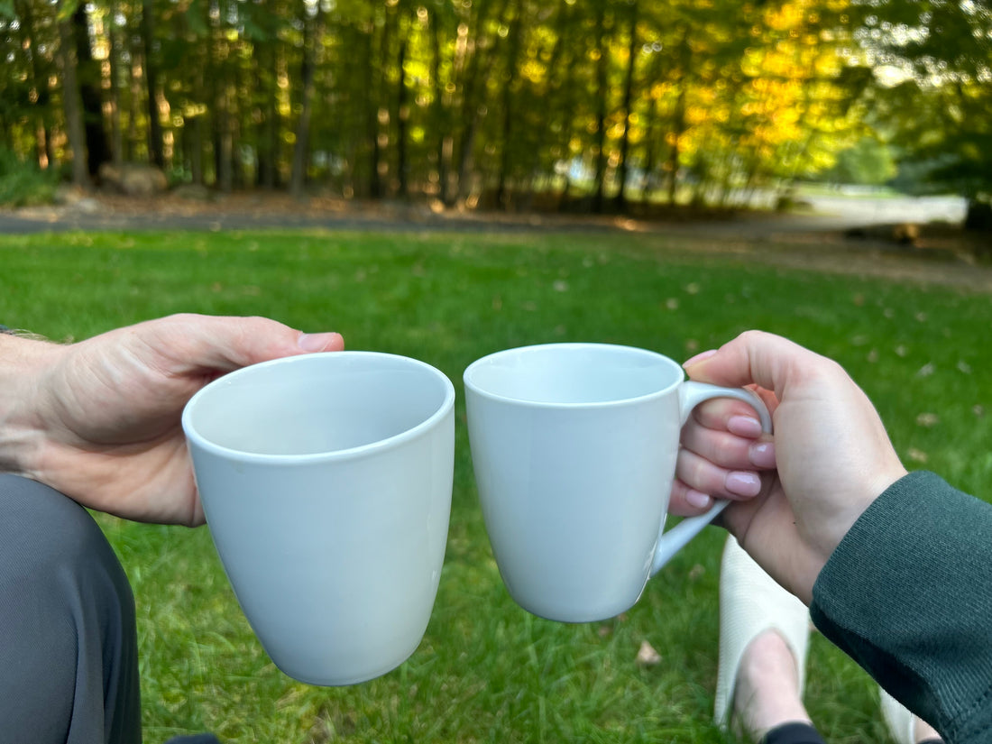 two coffee mugs held by two people in the front yard